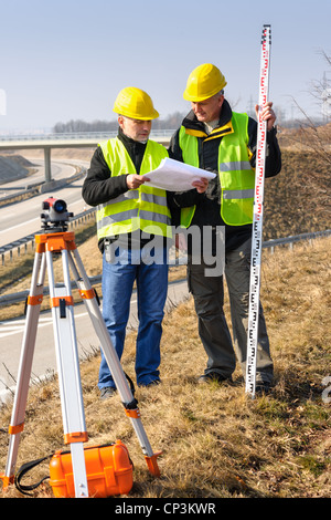 Geometri su autostrada geodesist lettura piani utilizzano tacheometer Foto Stock