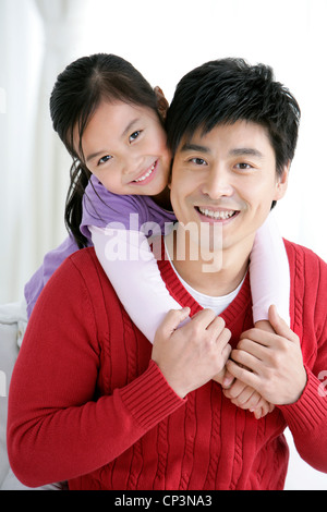 Figlia cinese abbracciando il padre da dietro Foto Stock