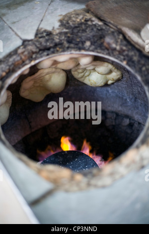 L M Rahman preparazione e cottura fresca pane naan nel forno tandoor a Karim's Restaurant, Delhi, India Foto Stock