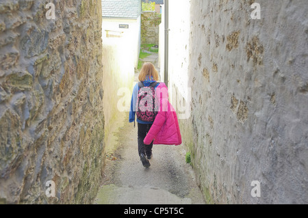 Un 9 anno vecchia ragazza cammina a scuola sotto la pioggia nel lavaggio, Cornwall, Regno Unito Foto Stock