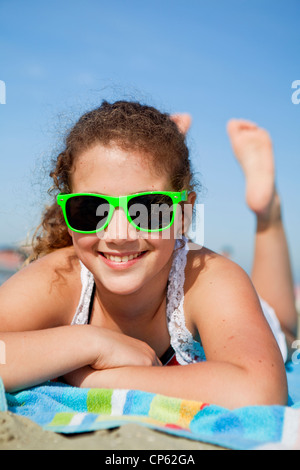 Felice adolescente posa su un telo da spiaggia in riva al mare Foto Stock