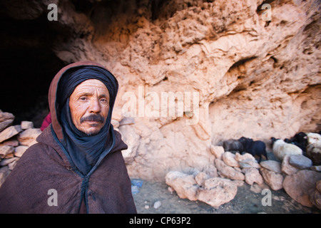 Un pastore berbero emergente da una grotta dove il suo gregge ha ospitato per la notte nella anti Atlas del Marocco. Foto Stock