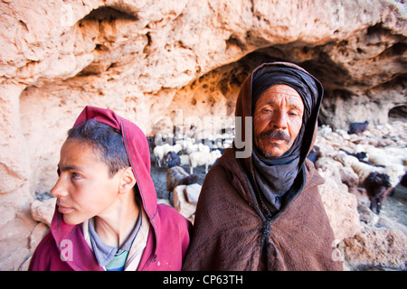 Un pastore berbero emergente da una grotta dove il suo gregge ha ospitato per la notte nella anti Atlas del Marocco. Foto Stock