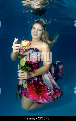 Una giovane donna con grandi capelli in posa di un subacqueo in piscina Foto Stock