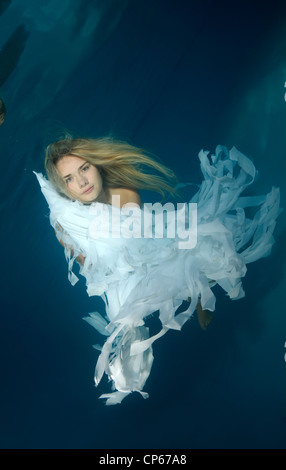 Una giovane donna con grandi capelli in posa di un subacqueo in piscina Foto Stock