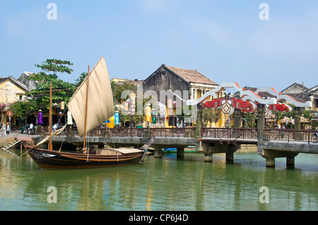 Vista orizzontale della tradizionale vietnamita in barca da pesca con la vela fino ormeggiate vicino alla parte sollevabile gio Bồn River Bridge a Hoi An, Vietnam. Foto Stock
