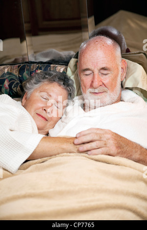 Coppia senior addormentato nel letto, tenendo le mani. Vista verticale. Foto Stock