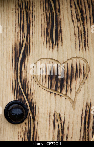 Porta di legno con un cuore scolpito in Foto Stock