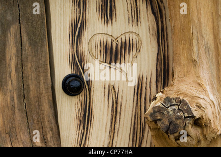 Porta di legno con un cuore scolpito in Foto Stock