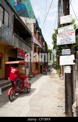 Camera in affitto dei manifesti in una strada laterale, fornitore di gelati in sella passato sul suo trisikad. Cebu City Cebu, Visayas nelle Filippine. Foto Stock