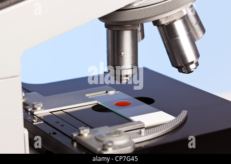 Foto di un microscopio da laboratorio con un campione di sangue su un vetrino di vetro. Foto Stock