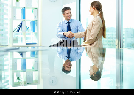 Formalmente vestiti giovani lo handshaking dopo accordo in ufficio Foto Stock