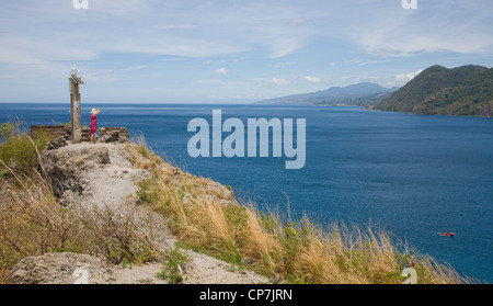 Una ragazza in un abito rosso si affaccia sulla baia di Soufriere da una luce di spedizione vicino a Scott di testa in Dominica Foto Stock