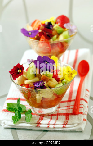 Macedonia di frutta con mela cotogna e petali di fiori. Ricetta disponibile. Foto Stock