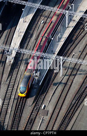 Vista panoramica di un treno in avvicinamento una stazione, sidelit nella luce del mattino. Foto Stock