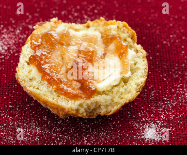 Home reso scone con burro e marmellata di rosso su rosso la tovaglia Foto Stock