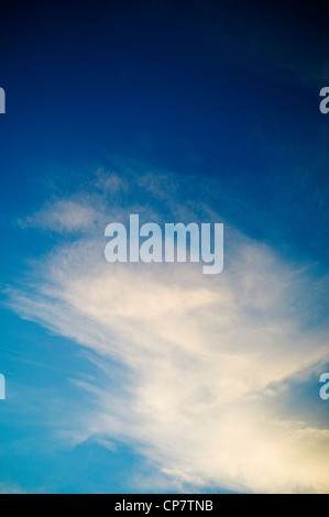 Bianche nuvole al tramonto attraverso un chiaro tramonto cielo blu Foto Stock