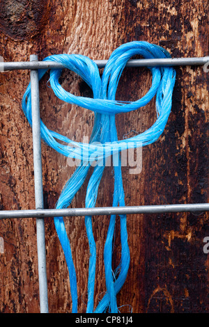 Un blu brillante di alimentazione è avvolto in un nodo loos intorno a un recinto di filo. Foto Stock