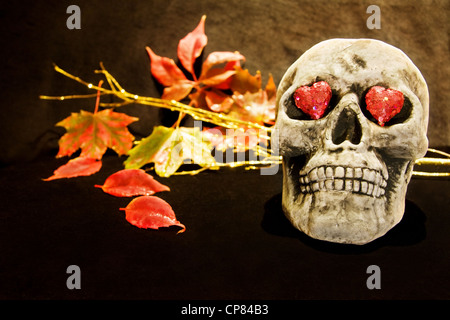 Celebrare la notte di Halloween con scary cranio e cuori rossi. Foto Stock