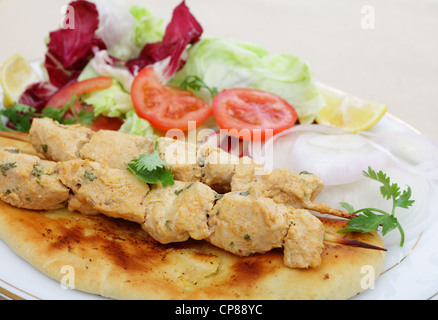 Pollo Tikka spiedini servita su in casa pane Naan flatbread con insalata Foto Stock