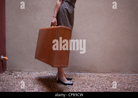La donna che porta una valigia vintage. Foto Stock