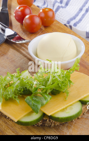Fetta di pane multigrain con formaggi stagionati e fette di cetriolo Foto Stock