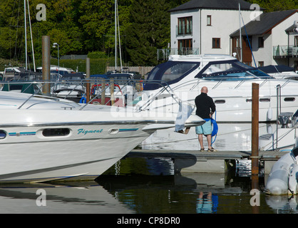 Uomo che pulisce la sua barca in Windermere Marina, vicino a Bowness, Parco Nazionale del Distretto dei Laghi, Cumbria, England Regno Unito Foto Stock
