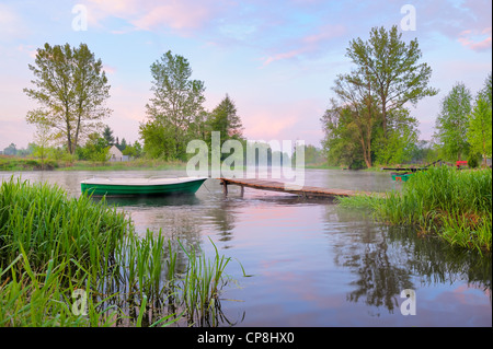 Paesaggio rurale con la barca e passerella sul fiume Narew dopo la nebbia, Polonia. Foto Stock