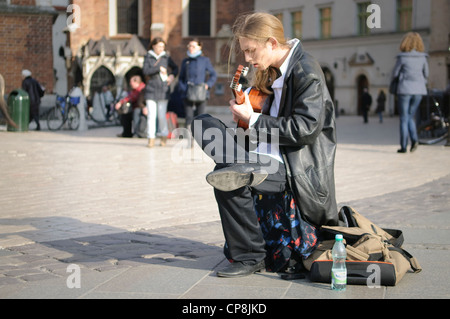 Un suonatore ambulante maschio a suonare la chitarra in Piazza del Mercato di Cracovia, in Polonia. Foto Stock