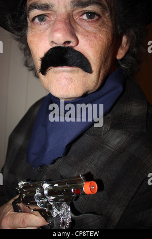 A cinquanta anni di vecchio uomo vestito da cowboy per una festa in costume verticale di sfondo semplice BDA Foto Stock