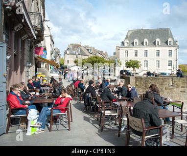 Persone seduti all'aperto in un café francese a Place Duclos, a Dinan, Bretagne, Francia Foto Stock