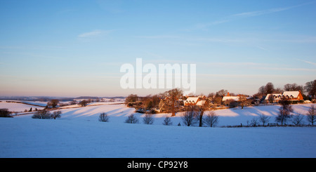 Vista attraverso i campi innevati all'alba verso il grazioso villaggio di appendere Houghton in Northamptonshire, England, Regno Unito Foto Stock