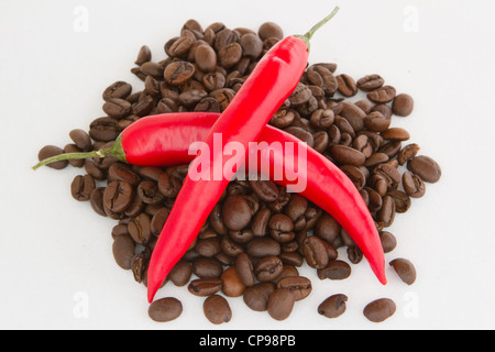 Due chili peppers giacente su freschi chicchi di caffè Foto Stock