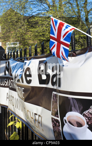 Piccola britannica Union Jack flag bloccato in ringhiere al di sopra di un banner pubblicitario Foto Stock