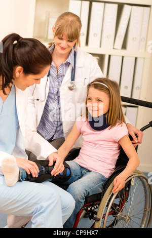 Piccola ragazza ferita su una sedia a rotelle con i medici presso ufficio medico Foto Stock