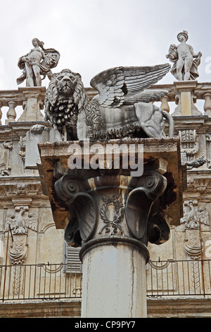 Statua di un leone alato su una colonna, di fronte a due altre statue sulla facciata di un edificio, Verona Italia Foto Stock