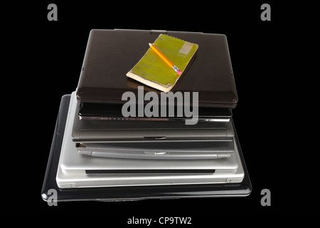 Pila di computer portatili con pastiglia usurata & matita sulla parte superiore Foto Stock