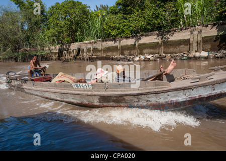 Il vietnamita uomini che viaggiano in una lunga barca, tra Cai Be e Vinh Long, Fiume Mekong Delta, Vietnam Foto Stock