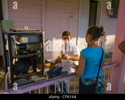 Un uomo che aziona un home business di vendita di gelato dalla sua parte anteriore portico in Viñales Cuba vende un cono ad una ragazza. Foto Stock