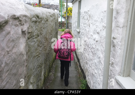 Un 9 anno vecchia ragazza cammina a scuola sotto la pioggia nel lavaggio, Cornwall, Regno Unito Foto Stock