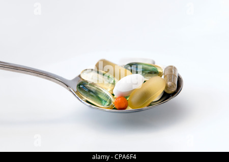 Selezione di vitamine (omega 3, Co-enzima Q10, menta piperita, condroitina, ginkgo e ginseng) sul cucchiaio su sfondo bianco. Foto Stock