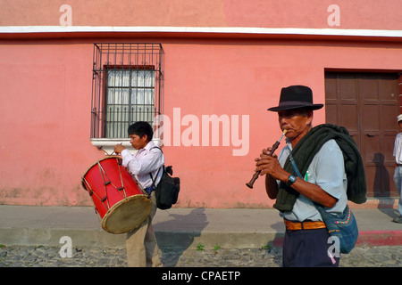 Guatemala Antigua muovendo luminosa colorata scena di strada a piedi con musicisti di suonare il tamburo e il flauto sito Unesco Foto Stock