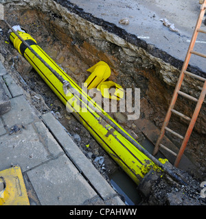 Sezione del vecchio tubo sotterraneo in ghisa rimossa per il nuovo gas principale in plastica gialla per passare attraverso meno lavori di scavo & strada Shenfield Essex Inghilterra UK Foto Stock