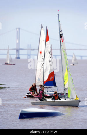 Approccio velisti una barca capovolta in una regata sul fiume Severn con il primo Severn Bridge più vicina e seconda Severn crossi Foto Stock