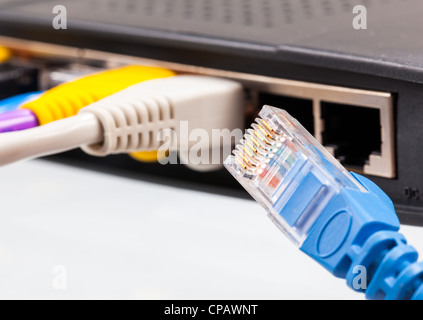 Macro shot di tappi su cavi CAT5e di molti colori isolati contro uno sfondo bianco inserito nel router Foto Stock