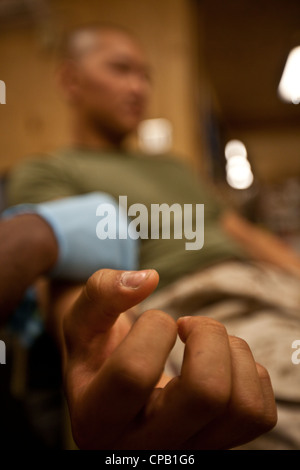 Lancia CPL. Meng Lu dona sangue per un soldato nazionale dell'esercito afgano in attesa in un'altra stanza della base operativa di Forward Delaram IIÂ€™s Shock Trauma Platoon, 8 maggio 2012. Il solider ANA ha fatto scalzare su una piastra di pressione all'inizio della mattina, mettendo in funzione un dispositivo esplosivo improvvisato. A causa della donazione di Lu e di altri due donatori, i medici si aspettano che il soldato viva. I corpmen, gli infermieri e i medici della Marina hanno dovuto sostituire quasi tutto il sangue di patientâ€™a causa della sua ferita. Foto Stock