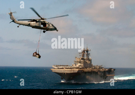 Un elicottero Sea Hawk MH-60S trasporta il carico alla nave d'assalto anfibia USS Makin Island (LHD 8) durante un rifornimento in mare con l'oliatore di rifornimento della flotta del comando militare di Sealift USNS Patuxent (T-AO 201). Makin Island Amphibious Ready Group è stato implementato per supportare le operazioni di sicurezza marittima e gli sforzi di cooperazione per la sicurezza del teatro nella 5° area di responsabilità della flotta statunitense. Foto Stock