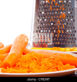 In prossimità della piastra con carote e grattugia, su sfondo bianco con copia spazio. Foto Stock