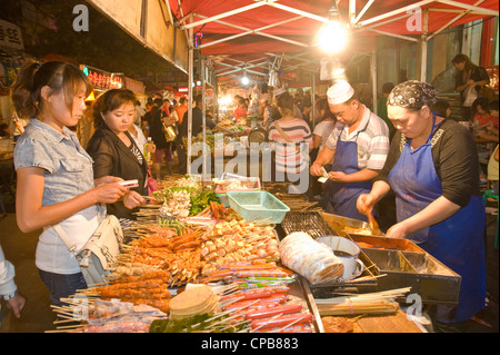 La vendita di snack alimentare alla ben nota Strada Zhengning notte food street market a Lanzhou. Foto Stock