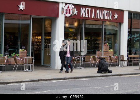 I lavoratori della città passano davanti a un senzatetto che implorava fuori da un negozio di panini Pret a Manger, evidenziando il divario tra ricchi e poveri e la disuguaglianza a Londra, Regno Unito Foto Stock